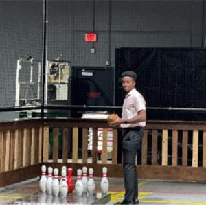 Truman holding a ball next to bowling pins.
