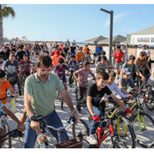 A large group of children and adults on bikes outside.