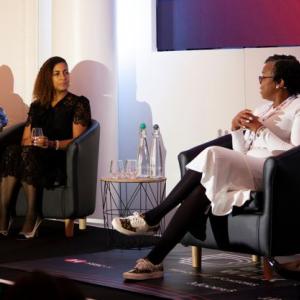 Three people seated on a stage, talking