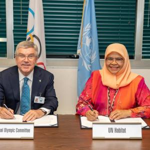 Two people sat at a desk signing a book
