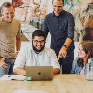 Four coworkers at a table working with laptops.