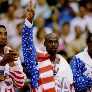 three athletes in USA uniform. medals around their necks. Spectators in the stands behind them.