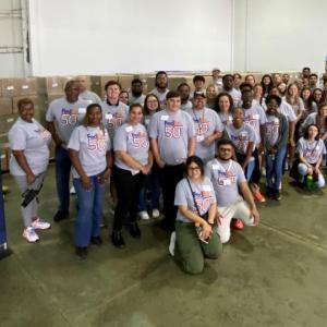 Group posed in a large space, a USO sign to the side.