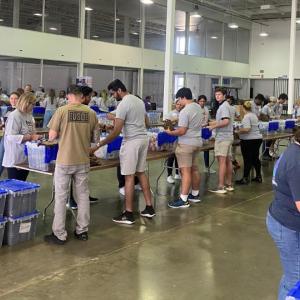 People organized at tables assembling kits.