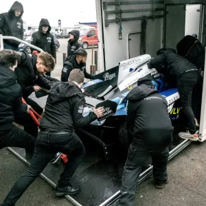 People helping push a motorsport car into a lorry