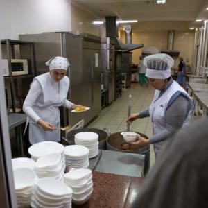 two people serving food from a kitchen
