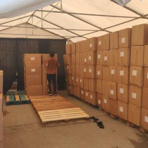 under a tent, many rows of stacked boxes