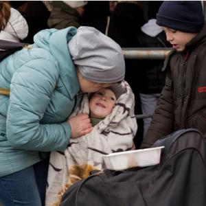 A mother plays with and puts a cover on her son on the way between Medyka and Przemyśl in Poland. (Photo by Oscar Castillo for Direct Relief)
