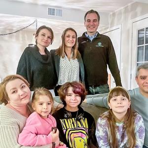 Regions associates stand behind the family sitting on a couch.