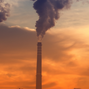 Industrial smoke pumped into a sunset, cloudy sky