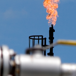 factory or plant emitting a tall flame into a clear, blue sky