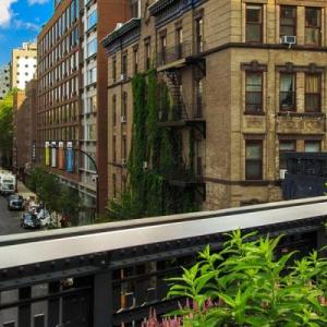 Panoramic view of an urban city with tall, close buildings. An elevated train line running through it. Greenery on the side.