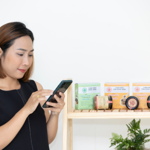 A person using a cell phone, a shelf of products on the right.