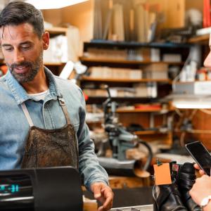 Veteran business owner shown ringing up a sale in his shop.