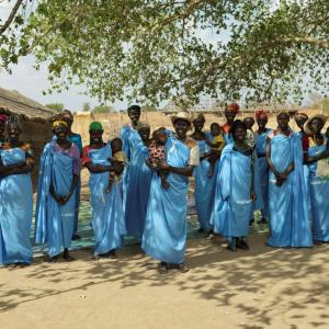 Women wearing blue smile for a photo. 