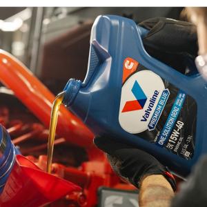 A person pouring a bottle of motor oil 