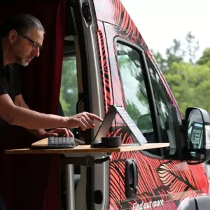 A person working on a laptop out of the side of a van.