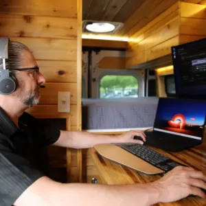 A person inside the van working on a tablet with other computer screens.