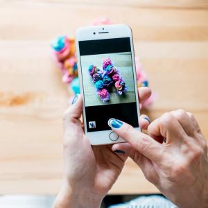 Person holding an iPhone and taking a photo of a flower.