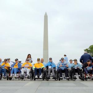 A line of people in wheelchairs and others behind them in front of the washington monument