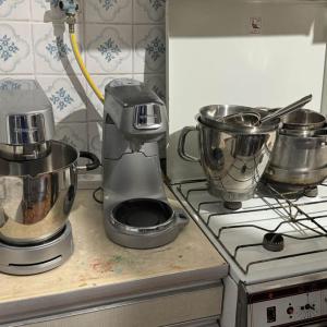 Silver mixers and bowls on a counter and stovetop.