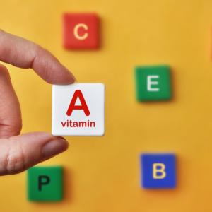 person holding up a block reading "A vitamin"