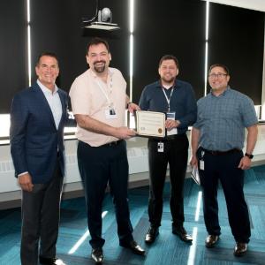 four people holding a certificate of achievement 