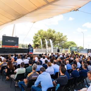 Large group sitting in front of stage in outdoor venue