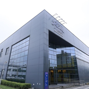 Exterior of an office building. A sign in a foreign language above the high front opening.