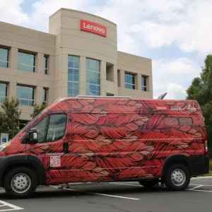 A colorful feather patterned van in a lot outside a Lenovo building.