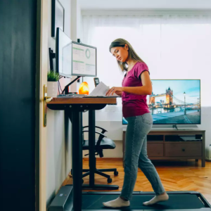 Woman at standing desk with walking treadmill underneath 
