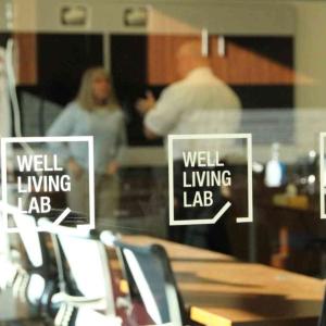 looking into the Well Living Lab from outside glass walls, two people talking inside