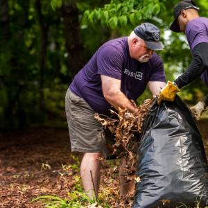 Two Truist volunteers stuffing debris into a bag.