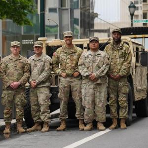 A group of members of the armed forces in front of an armored truck.