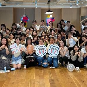 A large group of people posed for the camera. Some hold balloons or signs for Waffle College. 