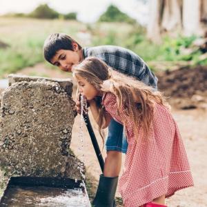 Girl and boy drinking from a fountain