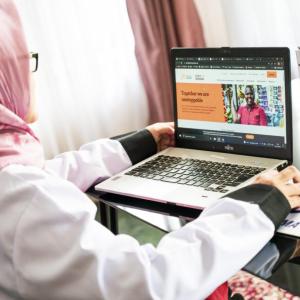 A person working on a laptop at a desk, open to the cherie blair foundation website