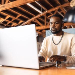 Male sitting in front of a laptop at a desk.