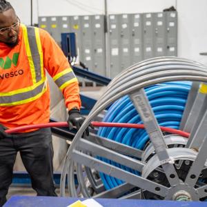 Wesco employee in safety gear reeling in a cable.