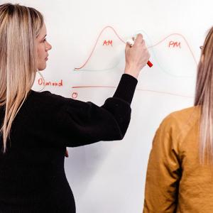 Laurel Meeks writing on a whiteboard, another looking on.