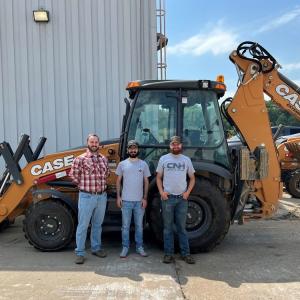 Three people standing in front of a large Case combo-loader