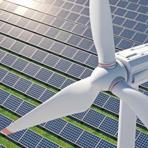 Windmill shown against a backdrop of solar panels.