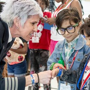 A pilot shakes the hand of a child in a line of others.