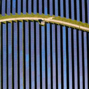 A field of solar panels is shown with a winding path in the middle of it.