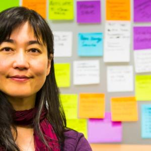 women with wall of post it notes behind her