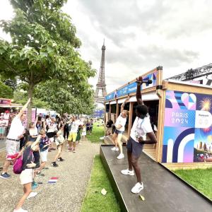 A crowd of people participating in a fitness activity, copying the movements of two people in front of them on a stage
