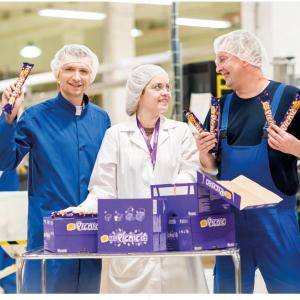 Three workers in their uniforms holding Mondelēz products