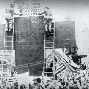 Two people on a ladder painting a cross 