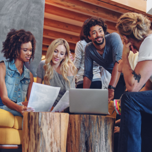 Four people seated together with open laptops, talking.