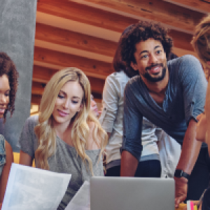 Four people seated together with open laptops, talking.